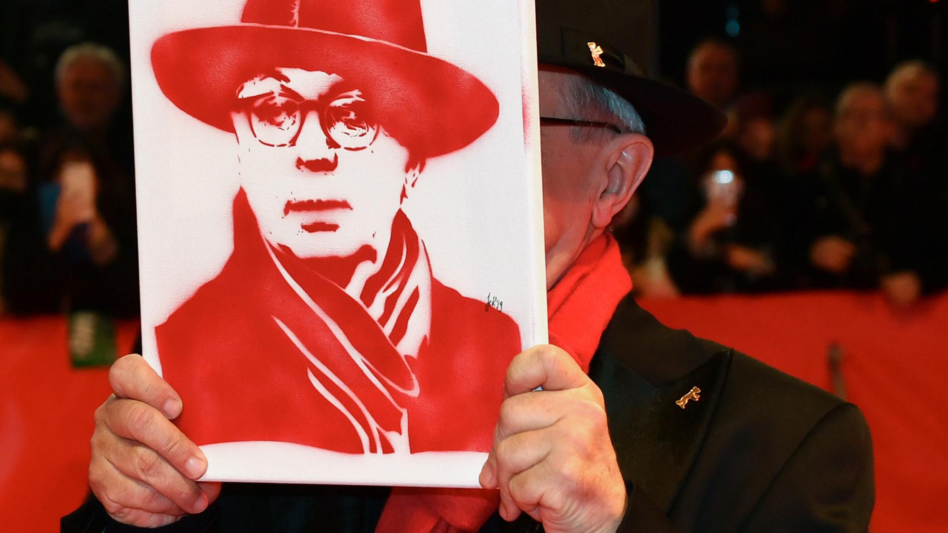 Abschluss der 69. Berlinale: Der scheidende langjährige Festivaldirektor Dieter Kosslick zeigt sich am roten Teppich mit einem Portrait von sich - natürlich ganz in rot