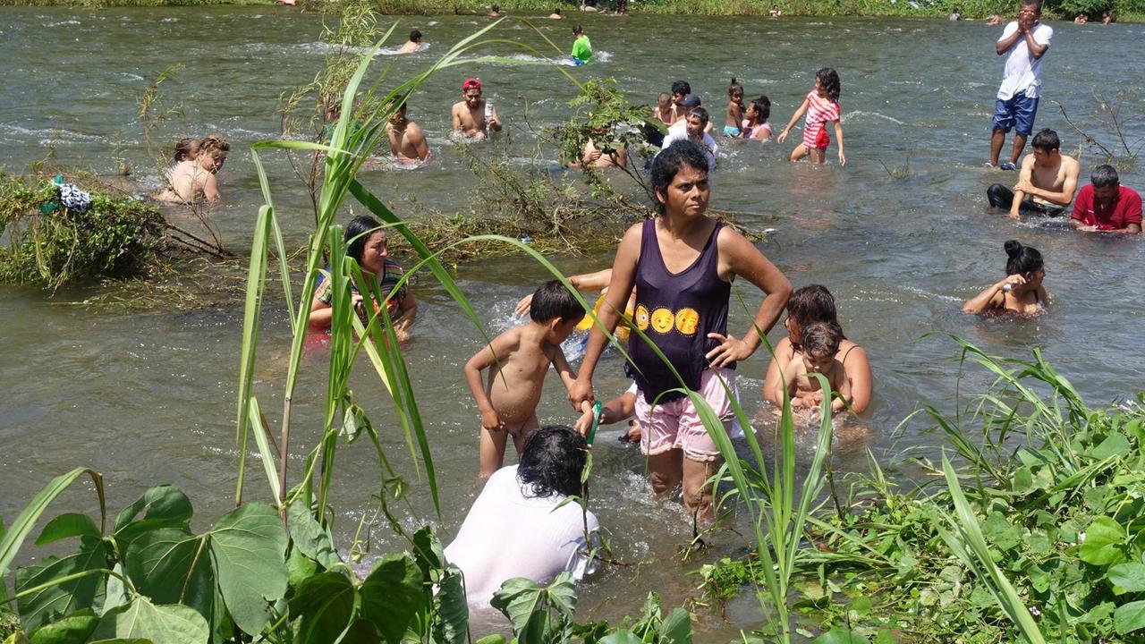 Frauen und Kinder baden in einem Fluss