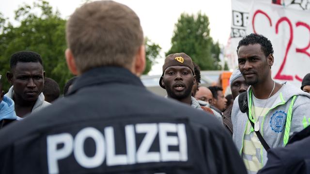 Flüchtlinge diskutieren am 25.8.2014 am besetzten Oranienplatz in Berlin mit Polizisten
