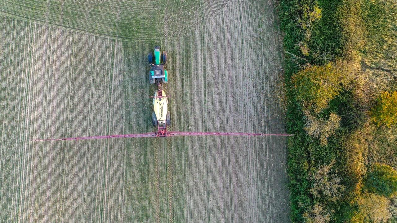Ein Landwirt fährt mit einer Pflanzenschutzspritze über ein Feld Ein Landwirt fährt mit einer Pflanzenschutzspritze über ein Feld