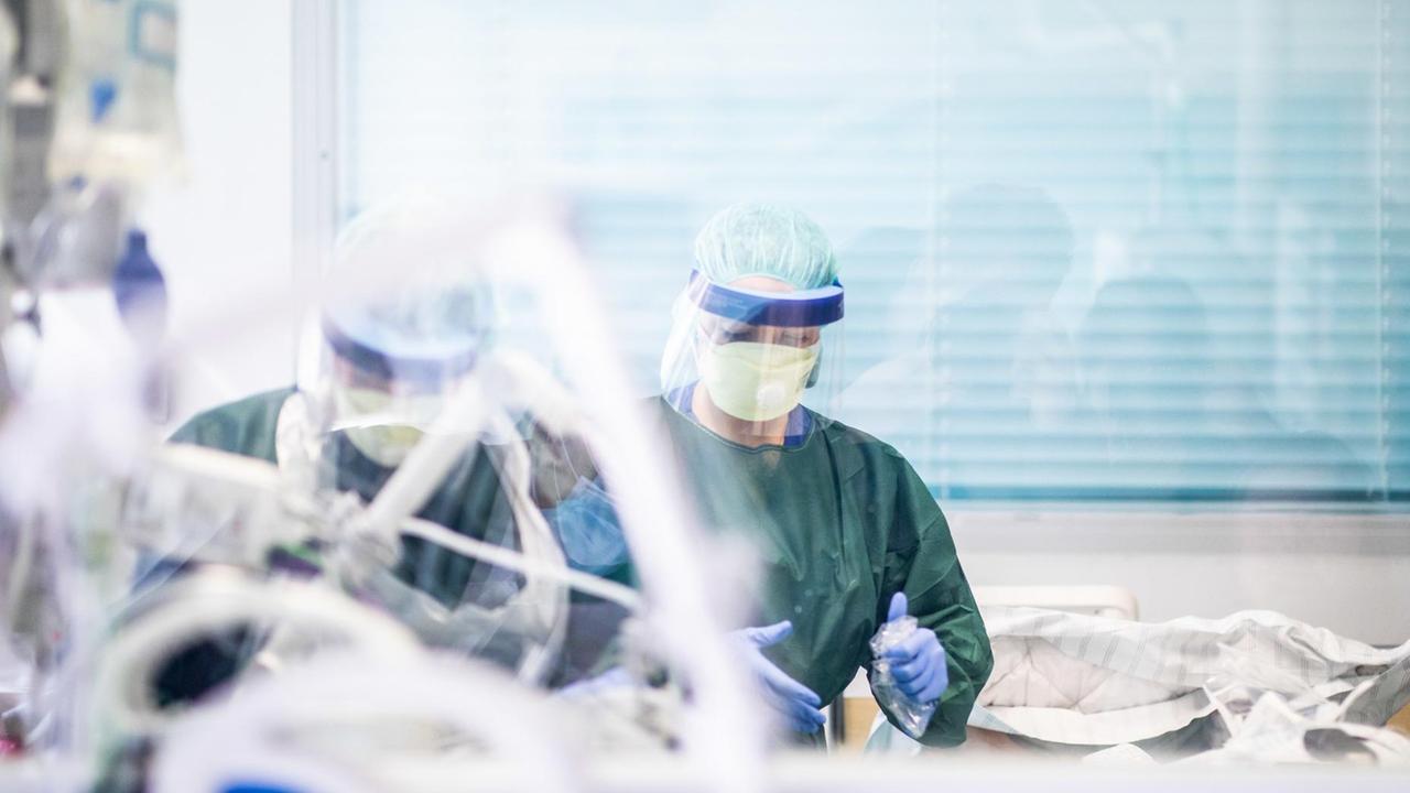 Zwei Krankenpfleger arbeiten in Schutzkleidung in einem Krankenzimmer auf der Intensivstation des Uniklinikums Essen, in dem ein Corona-Patient aus Frankreich behandelt wird. Zwei Krankenpfleger arbeiten in Schutzkleidung in einem Krankenzimmer auf der Intensivstation des Uniklinikums Essen, in dem ein Corona-Patient aus Frankreich behandelt wird.