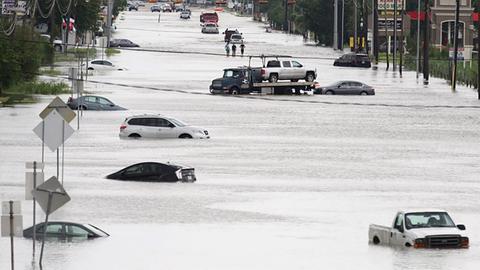 A car gets towed while men walk in the flooded waters of Telephone Rd. in Houston, Texas on August 30, 2017. Monster storm Harvey made landfall again Wednesday in Louisiana, evoking painful memories of Hurricane Katrina's deadly strike 12 years ago, as time was running out in Texas to find survivors in the raging floodwaters. / AFP PHOTO / Thomas B. Shea