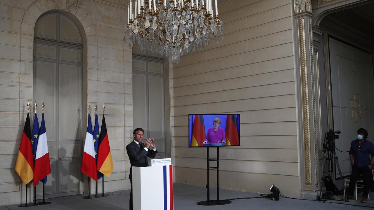 French President Emmanuel Macron speaks while German Chancellor Angela Merkel listens during a joint video press conference at the Elysee Palace, on May 18, 2020, in Paris.