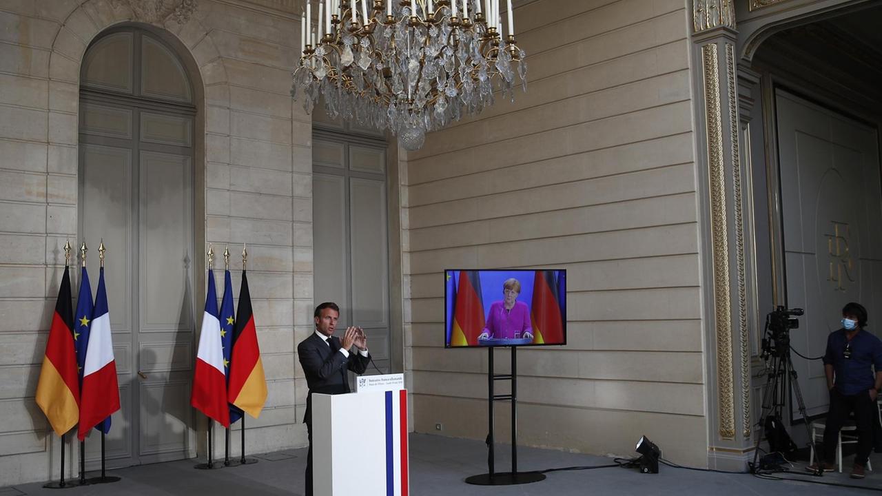 French President Emmanuel Macron speaks while German Chancellor Angela Merkel listens during a joint video press conference at the Elysee Palace, on May 18, 2020, in Paris. French President Emmanuel Macron speaks while German Chancellor Angela Merkel listens during a joint video press conference at the Elysee Palace, on May 18, 2020, in Paris.