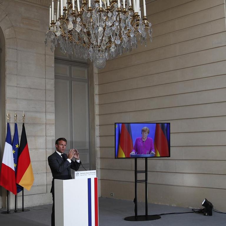 French President Emmanuel Macron speaks while German Chancellor Angela Merkel listens during a joint video press conference at the Elysee Palace, on May 18, 2020, in Paris.