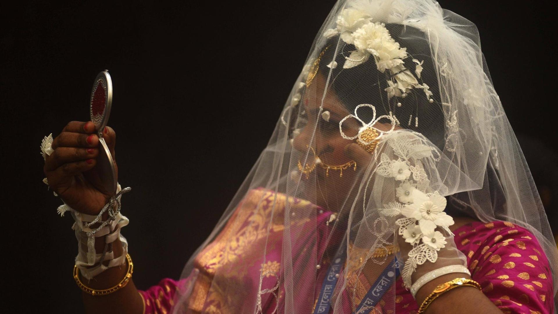 Eine Braut, die in einen kleinen Handspiegel schaut, aufgenommen während einer Massenhochzeit in Kolkata, Indien, am 14. Februar 2021 Eine Braut, die in einen kleinen Handspiegel schaut, aufgenommen während einer Massenhochzeit in Kolkata, Indien, am 14. Februar 2021