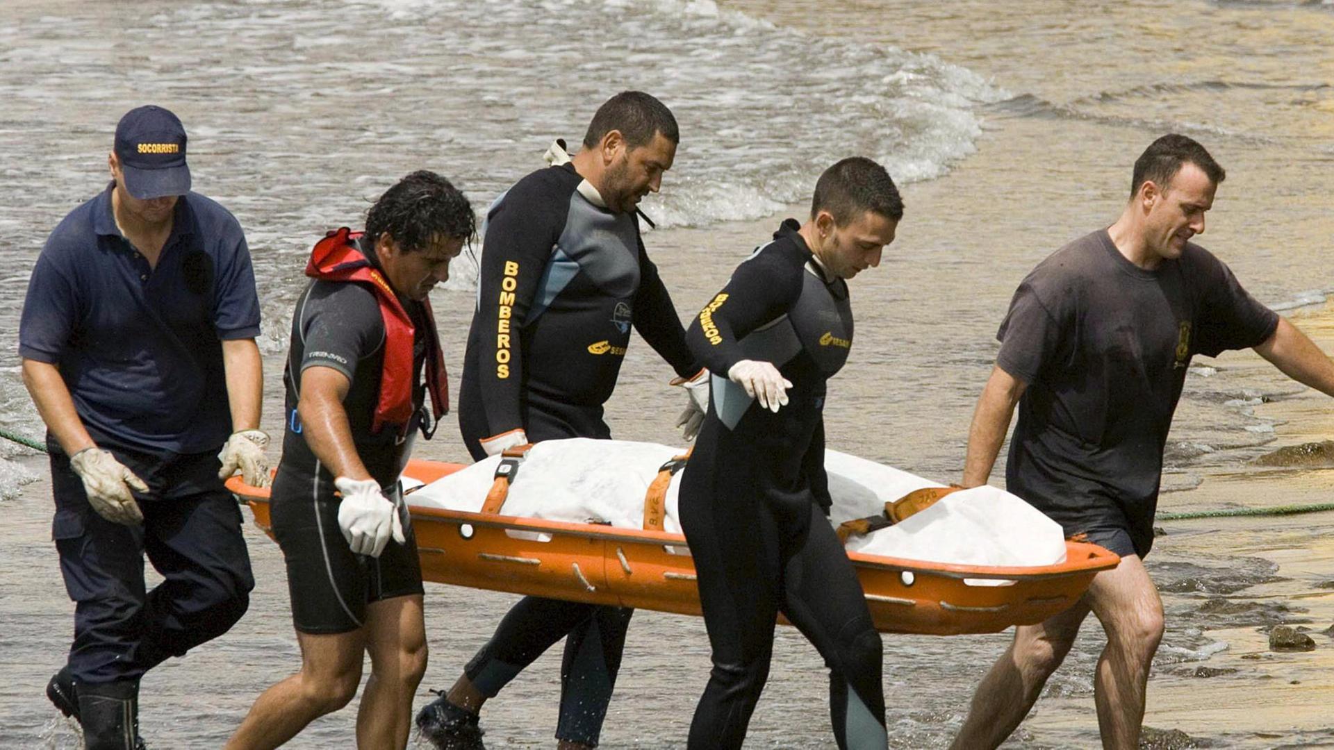 Feuerwehrleute tragen am Strand von Teneriffa den Leichnam eines ertrunkenen Flüchtlings aus Afrika Feuerwehrleute tragen am Strand von Teneriffa den Leichnam eines ertrunkenen Flüchtlings aus Afrika