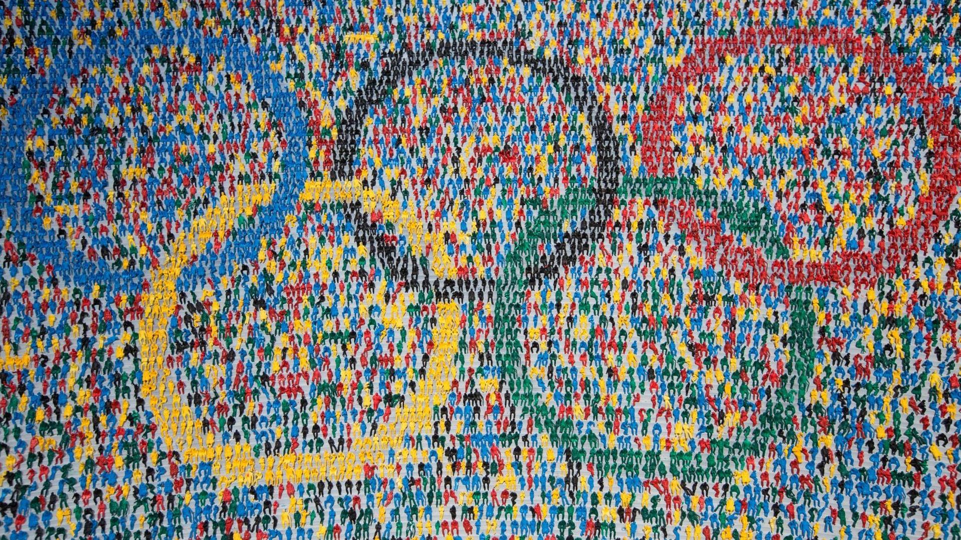 Die olympischen Ringe, zusammengesetzt aus Miniaturfiguren, die auf einer Tribüne sitzen Die olympischen Ringe, zusammengesetzt aus Miniaturfiguren, die auf einer Tribüne sitzen