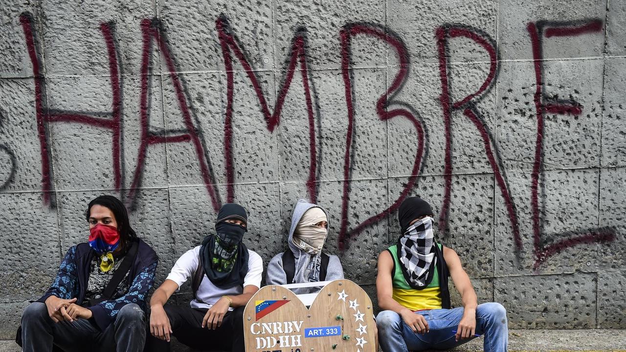 Oppositionelle Aktivisten sitzen vor einer einer Wand mit der Aufschrift "Hambre - Hunger" Oppositionelle Aktivisten sitzen vor einer einer Wand mit der Aufschrift "Hambre - Hunger"