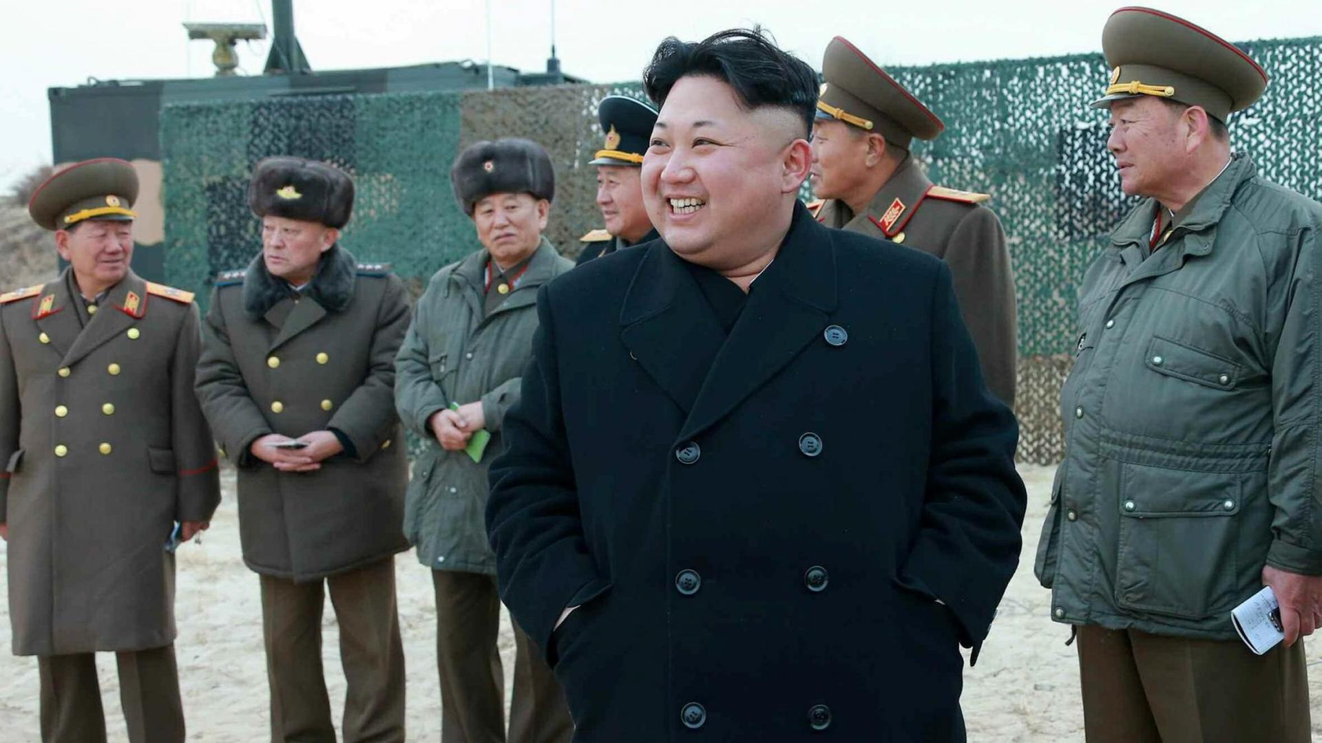 Kim Jong-un lachend im Kreis von uniformierten Männern.