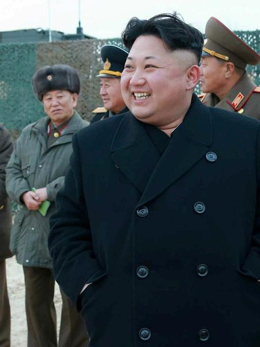 Kim Jong-un lachend im Kreis von uniformierten Männern.