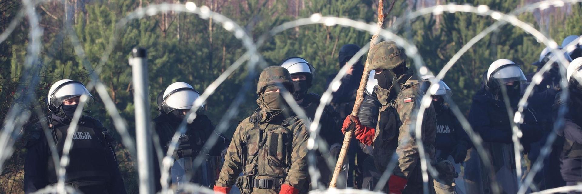 Polnische Sicherheitskräfte hinter Stacheldraht an der Grenze zu Belarus Polnische Sicherheitskräfte hinter Stacheldraht an der Grenze zu Belarus