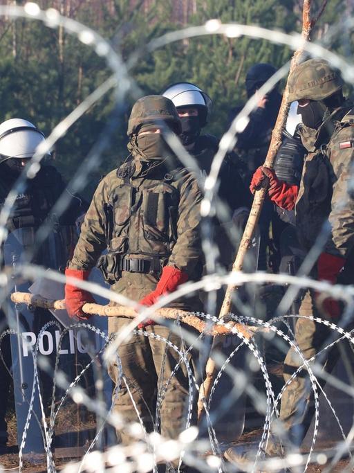 Polnische Sicherheitskräfte hinter Stacheldraht an der Grenze zu Belarus