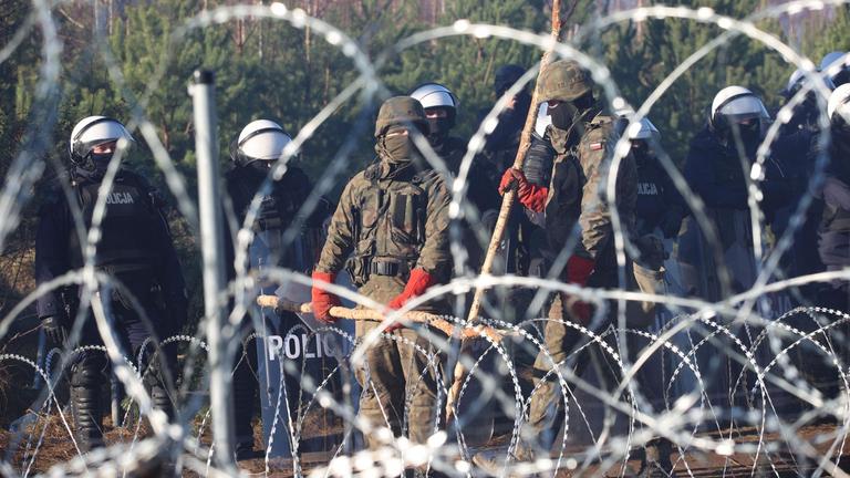 Polnische Sicherheitskräfte hinter Stacheldraht an der Grenze zu Belarus Polnische Sicherheitskräfte hinter Stacheldraht an der Grenze zu Belarus