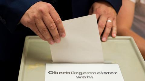 Dresdens Erster Bürgermeister Hilbert (FDP, l) wirft am 05.07.2015 in einem Wahlbüro in Dresden (Sachsen) seinen Stimmzettel zur Oberbürgermeisterwahl in eine Wahlurne.