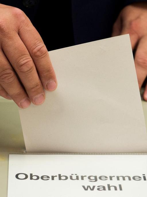 Stimmabgabe bei einer Oberbürgermeisterwahl. Einwurf des Stimmzettels an der Wahlurne.