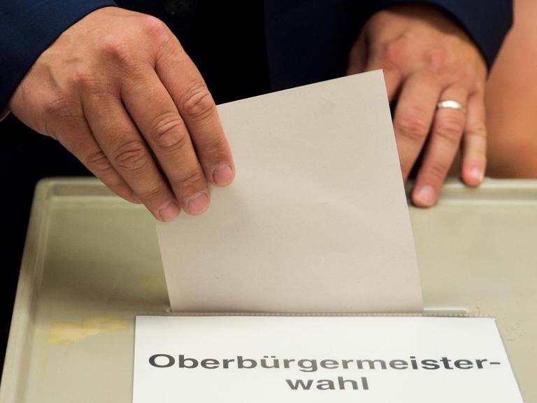 Stimmabgabe bei einer Oberbürgermeisterwahl. Einwurf des Stimmzettels an der Wahlurne.