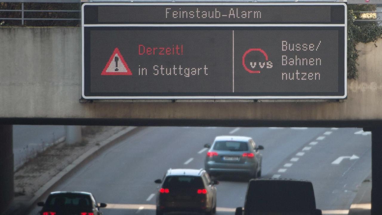 Autos fahren am 09.03.2016 in Stuttgart (Baden-Württemberg) durch die Innenstadt, während auf einer Anzeige ein Feinstaub-Alarm für die Umweltzone Stuttgart angezeigt und auf öffentliche Verkehrsmittel hingewiesen wird.
