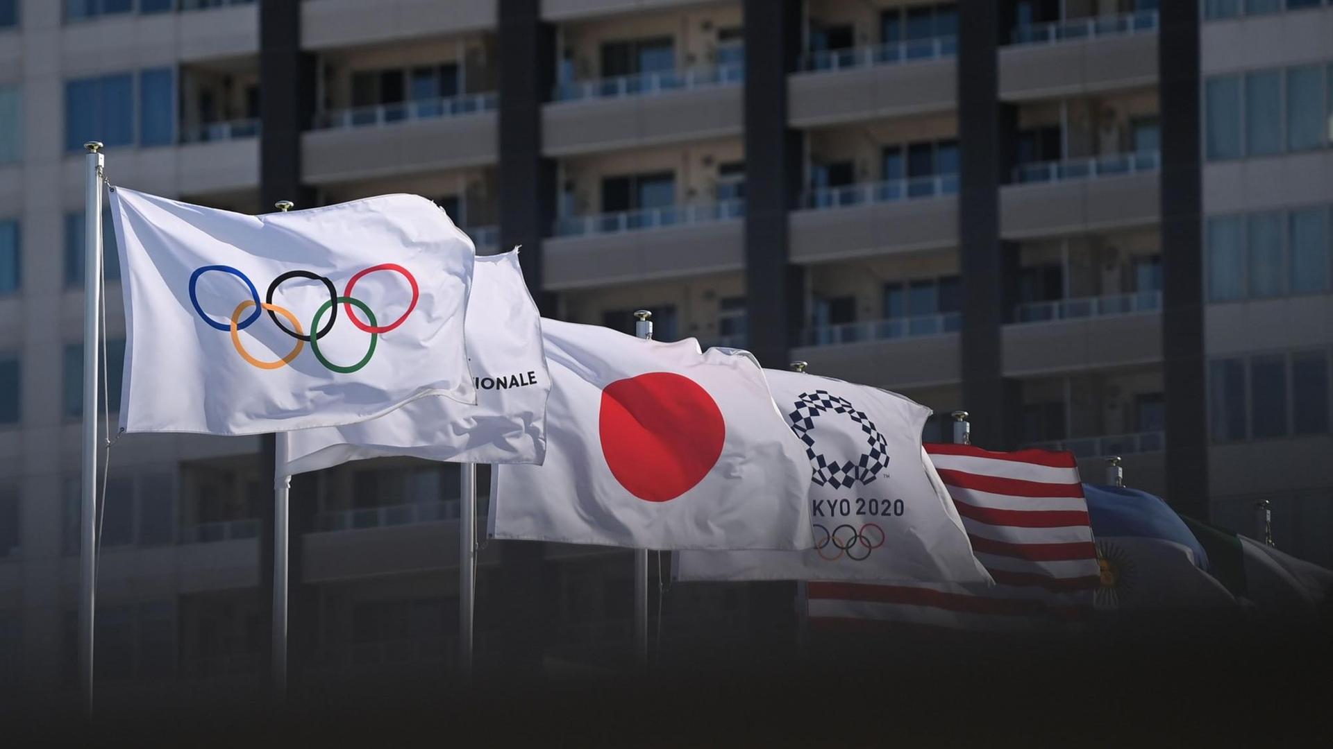 Die Olympische Flagge weht neben der japanischen und weiteren nationalen Flaggen im Wind. Die Olympische Flagge weht neben der japanischen und weiteren nationalen Flaggen im Wind.