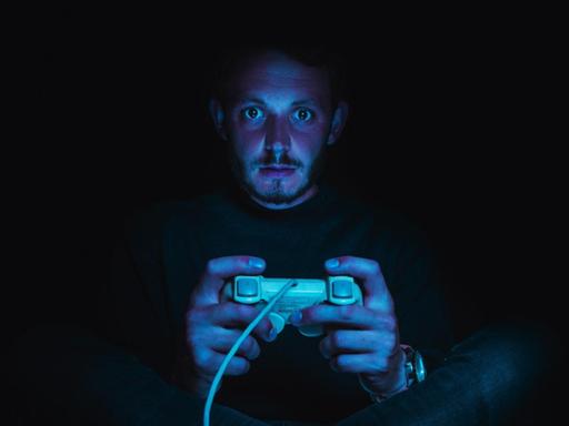 Ein Mann spielt im Dunkeln ein Computerspiel.