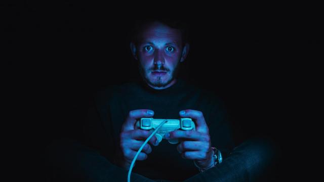 Ein Mann spielt im Dunkeln ein Computerspiel.
