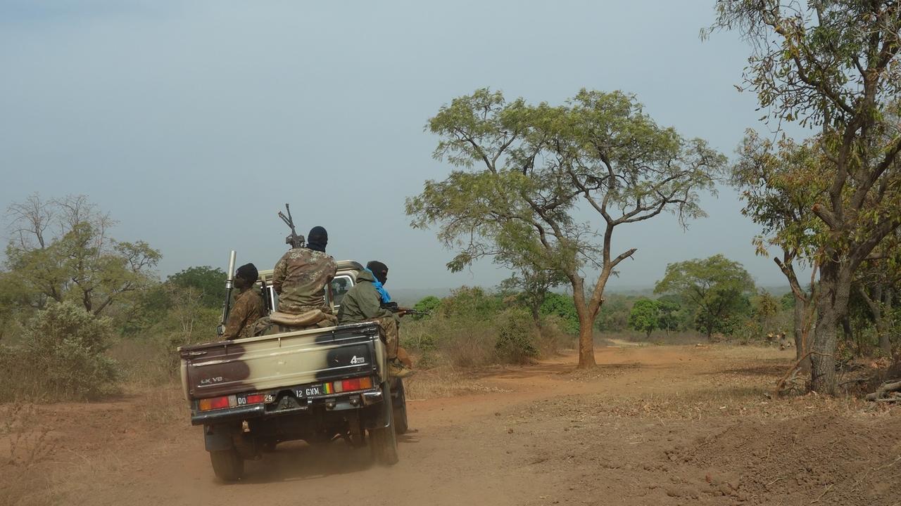 Ein Jeep mit drei bewaffneten Soldaten fährt übers Land. Ein Jeep mit drei bewaffneten Soldaten fährt übers Land.