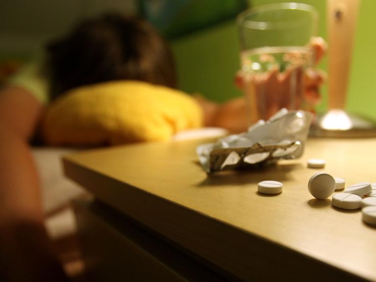 Tabletten liegen vor einem Bett