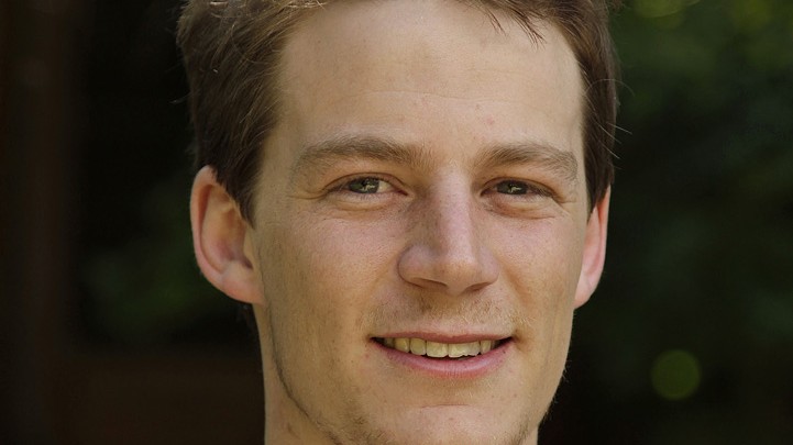 Ein junger Mann mit hoher Stirn lächelt in die Kamera. Ein junger Mann mit hoher Stirn lächelt in die Kamera.