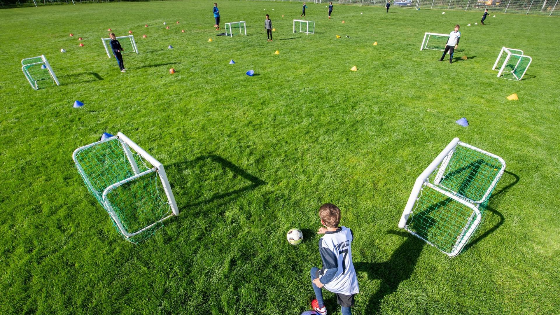 Junge Fußballer trainieren auf dem Spielfeld in großen Abständen.