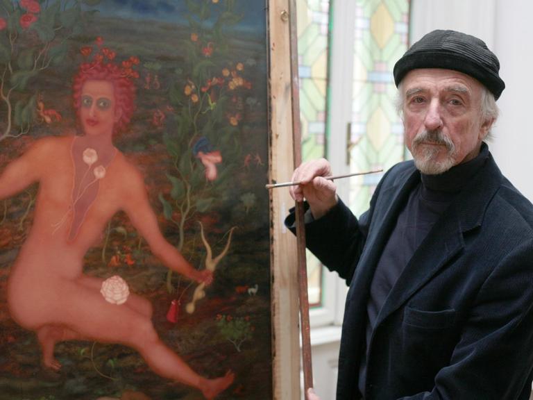 Der Maler Arik Brauer steht vor einem seiner bunten Bilder in seinem Atelier.