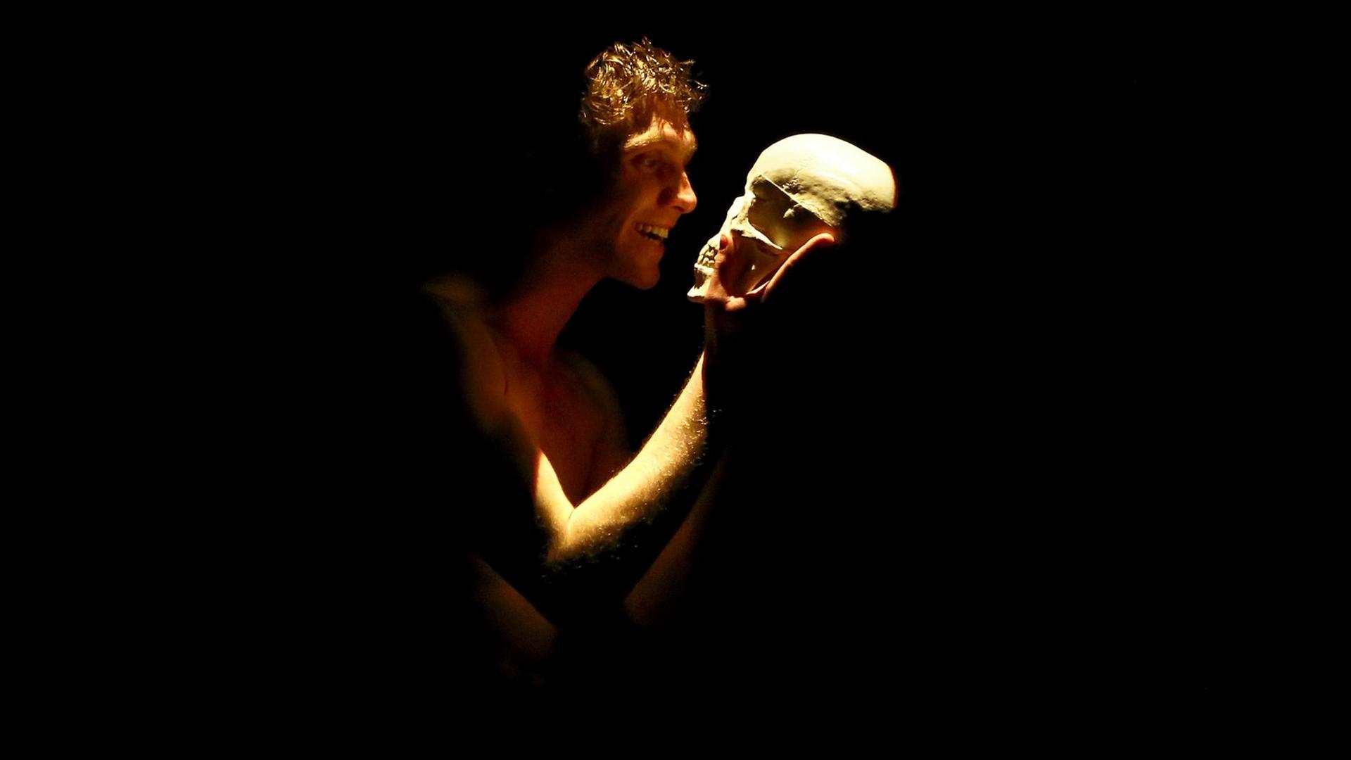 Johannes Nussbaum als Hamlet steht auf der Bühne und hält einen Totenkopf.