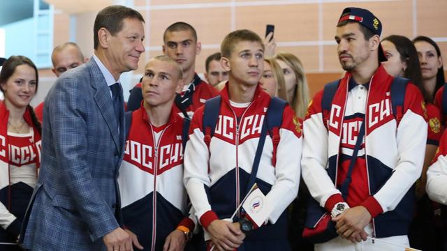 Alexander Schukow, Präsident des russischen Olympia-Kommittees, mit russischen Athleten am Flughafen in Moskau.