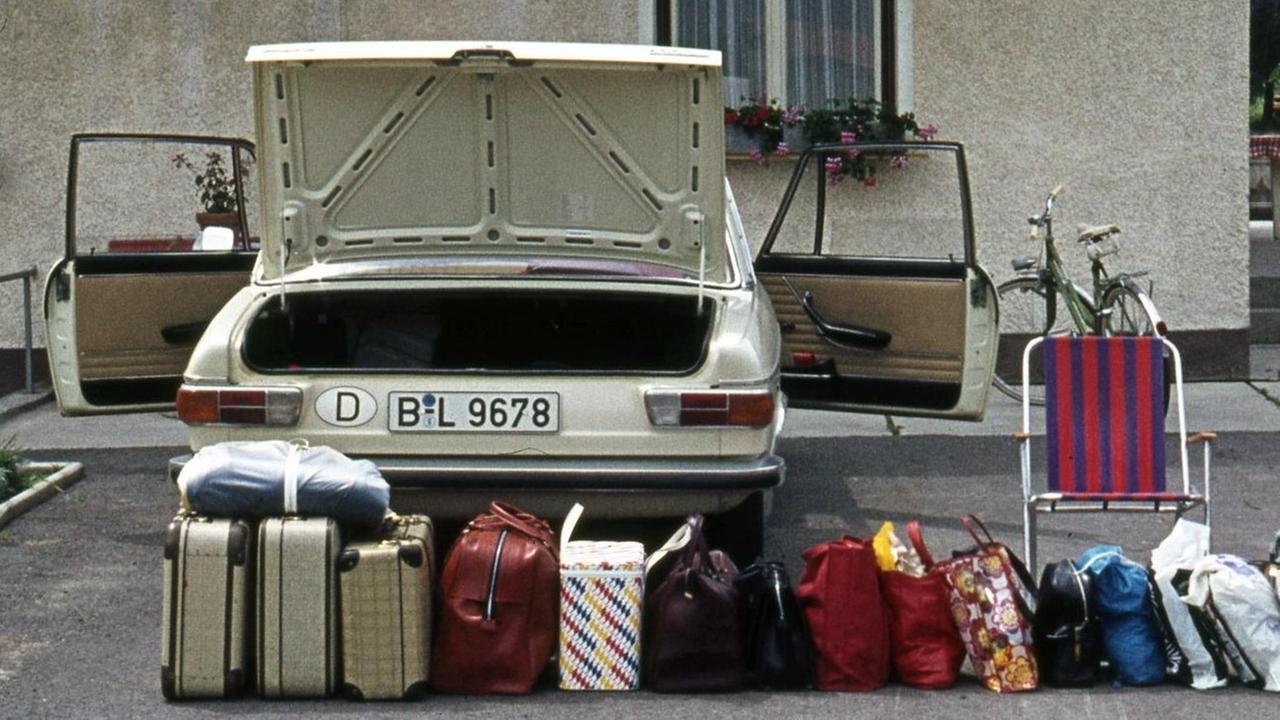 Ein Auto mit aufgereihten Koffern, Bild stammt aus den 1970er-Jahren Ein Auto mit aufgereihten Koffern, Bild stammt aus den 1970er-Jahren
