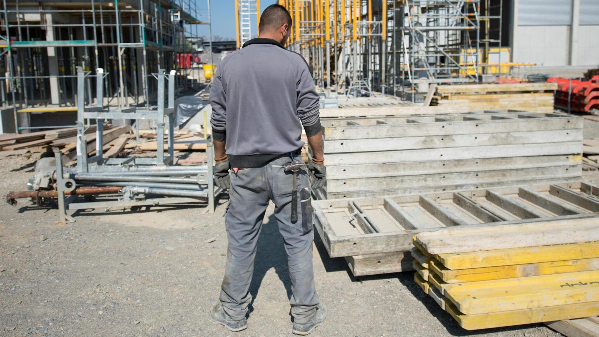 Ein Bauarbeiter sieht am 23.04.2015 auf Verschalungen für die Baustelle des neuen Wiegehauses am Recyclinghof in Winnenden (Baden-Württemberg). Ein Bauarbeiter sieht am 23.04.2015 auf Verschalungen für die Baustelle des neuen Wiegehauses am Recyclinghof in Winnenden (Baden-Württemberg).