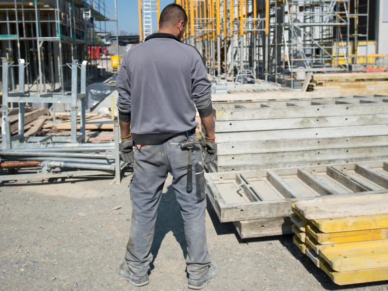 Ein Bauarbeiter sieht am 23.04.2015 auf Verschalungen für die Baustelle des neuen Wiegehauses am Recyclinghof in Winnenden (Baden-Württemberg).