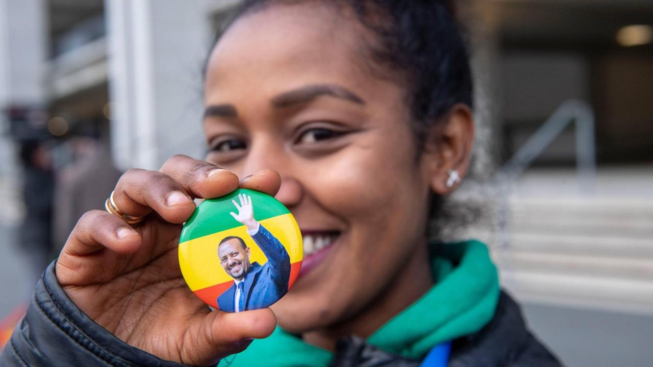 Eine junge Frau hält einen Ansteck-Button mit einem Porträt von Abiy Ahmed in die Kamera. Eine junge Frau hält einen Ansteck-Button mit einem Porträt von Abiy Ahmed in die Kamera.
