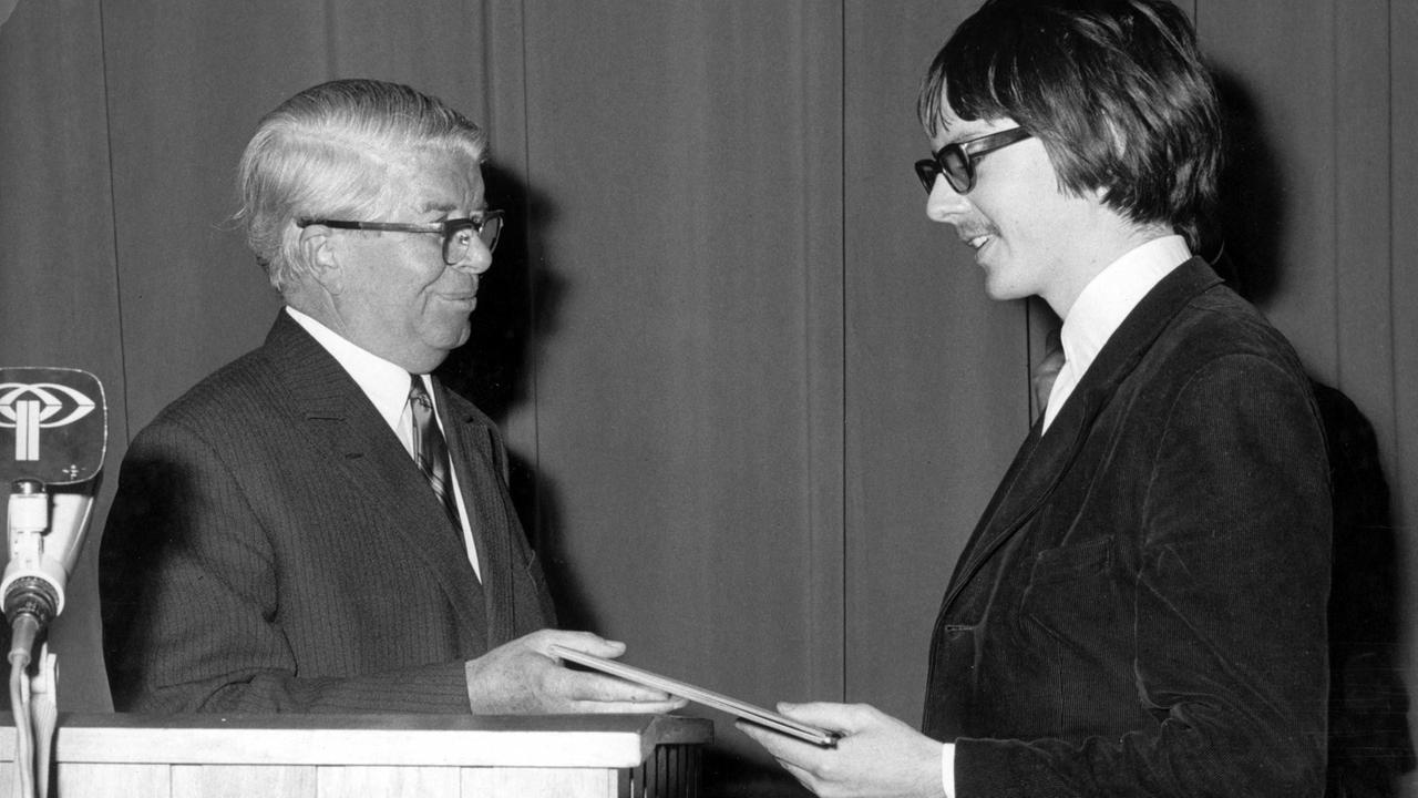 Der österreichische Schriftsteller Peter Handke (r) nimmt am 2. Dezember 1967 aus den Händen von Hermann Gressieker (l) den Gerhard-Hauptmann-Preis der Freien Volksbühne Berlin entgegen. Der österreichische Schriftsteller Peter Handke (r) nimmt am 2. Dezember 1967 aus den Händen von Hermann Gressieker (l) den Gerhard-Hauptmann-Preis der Freien Volksbühne Berlin entgegen.