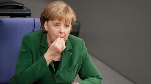 Bundeskanzlerin Angela Merkel (CDU) sitzt am 25.10.2012 in Berlin im Plenarsaal des Bundestages und führt die rechte Hand an den Mund. Der Bundestag beschäftigt sich in seiner Sitzung unter anderem mit den Themen Rentenbeitragssatz, Praxisgebühr, Steuerabkommen mit der Schweiz, Betreuungsgeld und der Höchstgrenze für Minijobs. Foto: Robert Schlesinger/dpa