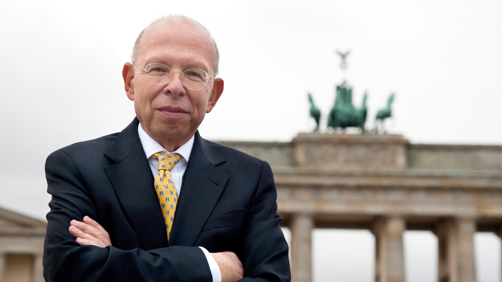 Porträt von Rafael Seligmann mit verschränkten Armen, im Hintergrund das Brandenburger Tor Porträt von Rafael Seligmann mit verschränkten Armen, im Hintergrund das Brandenburger Tor