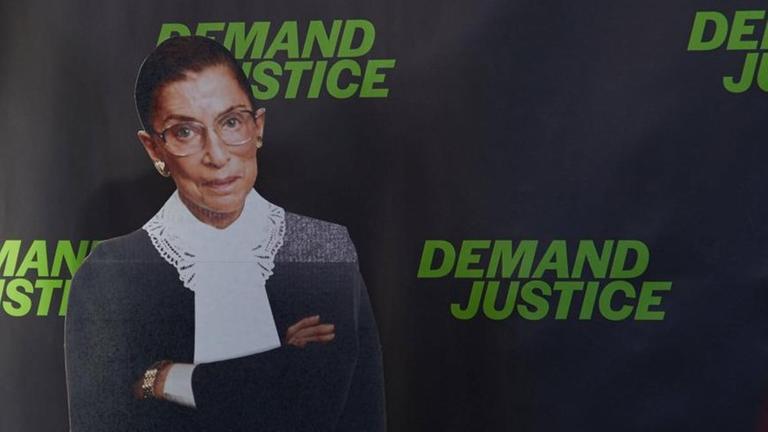 Die ehemalige Richterin des Supreme Courts der USA, Ruth Bader Ginsburg, als Fotoplakat-Figur vor einer schwarzen Wand, auf der wiederholt in grellgrüner Schrift "Demand Justice" - "Fordert Gerechtigkeit" steht. Die ehemalige Richterin des Supreme Courts der USA, Ruth Bader Ginsburg, als Fotoplakat-Figur vor einer schwarzen Wand, auf der wiederholt in grellgrüner Schrift "Demand Justice" - "Fordert Gerechtigkeit" steht.