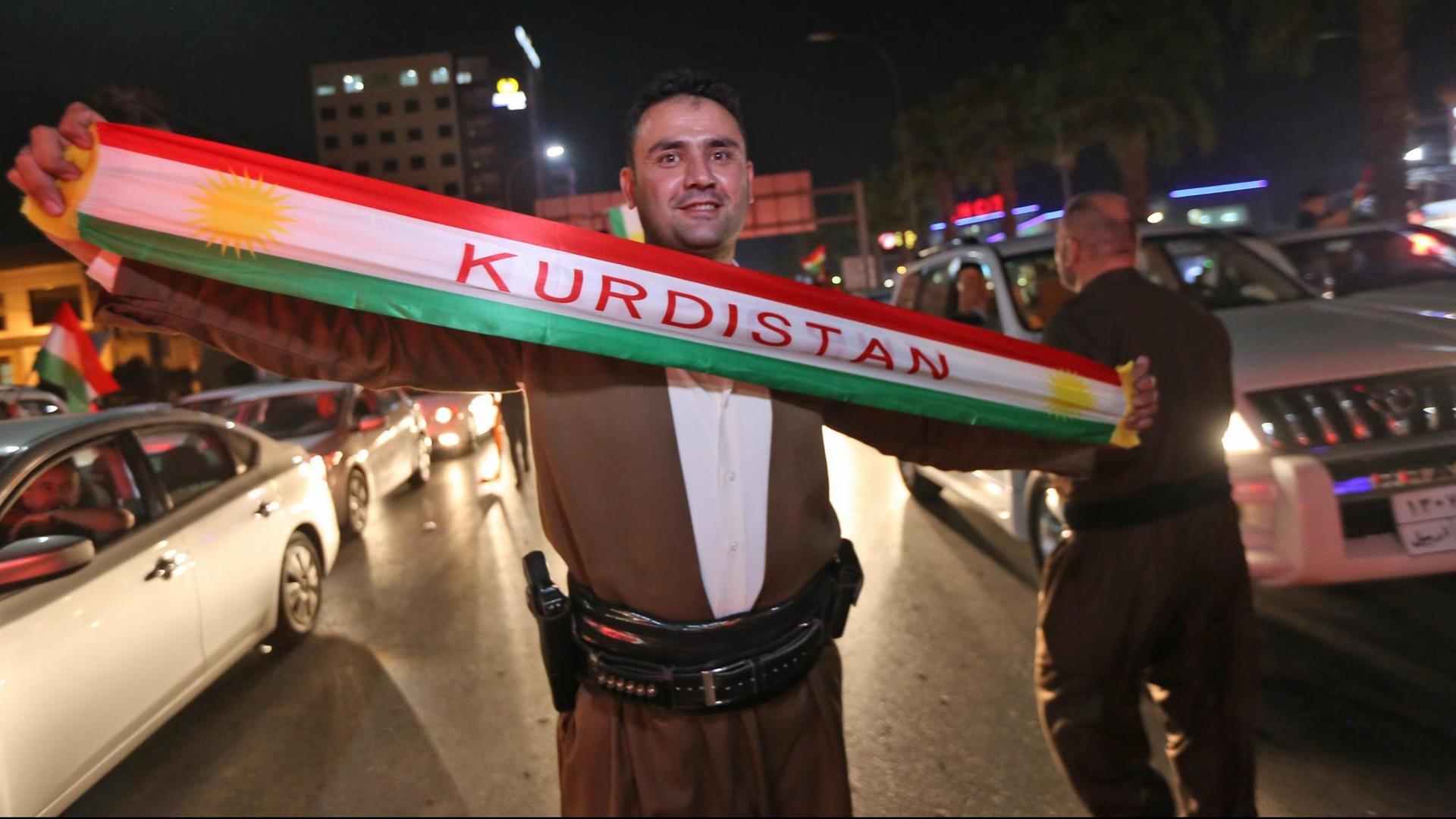 Ein Kurde im Nordirak hält nach dem Referendum ein Tuch mit dem Wort "Kurdistan" hoch.