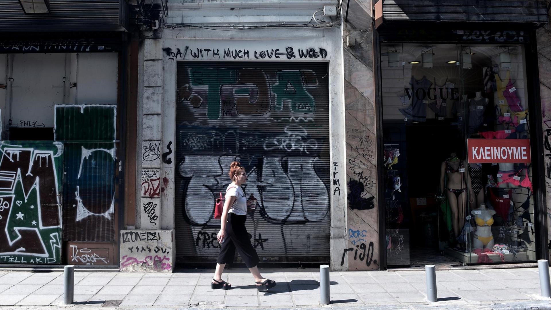 Eine Frau läuft in Thessaloniki an einen geschlossenen Geschäft vorbei. Eine Frau läuft in Thessaloniki an einen geschlossenen Geschäft vorbei.