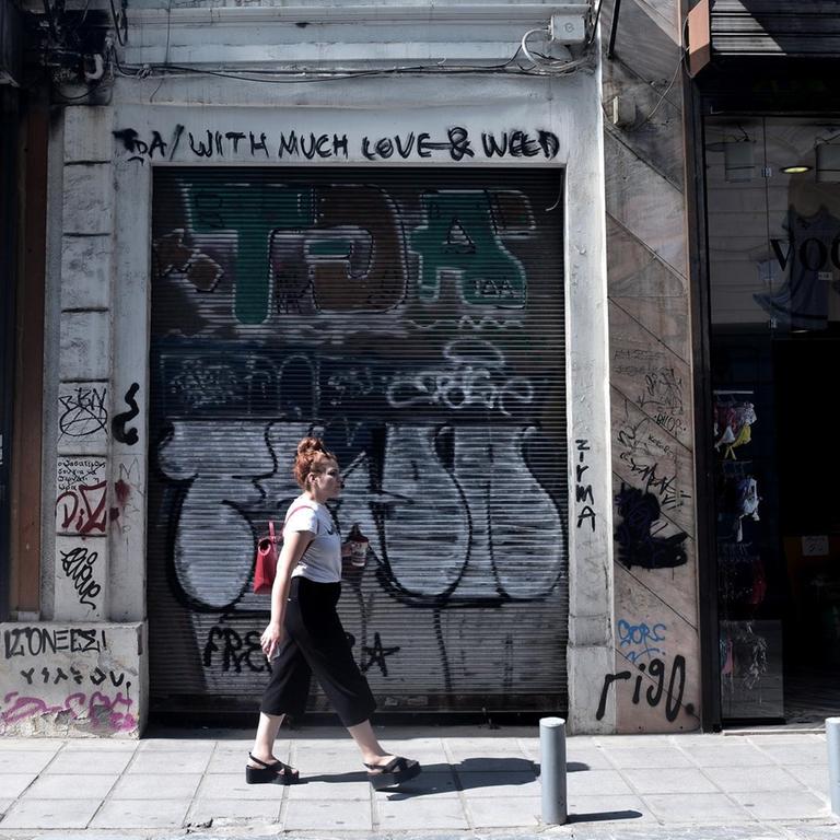 Eine Frau läuft in Thessaloniki an einen geschlossenen Geschäft vorbei. 