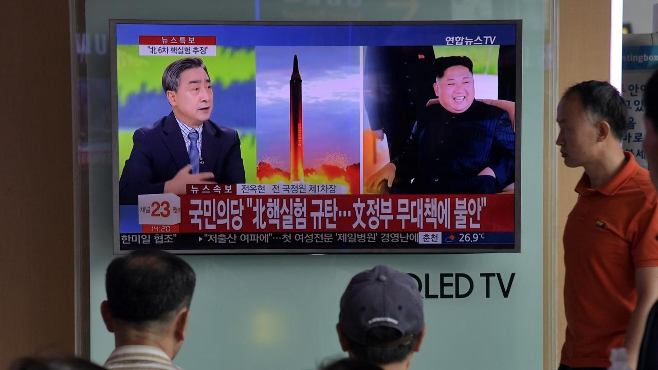 Menschen vor einem Fernsehgerät, auf dem über ein Raketenstart sowie der nordkoreanische Machthaber Kim Jong-Un gezeigt wird. Menschen vor einem Fernsehgerät, auf dem über ein Raketenstart sowie der nordkoreanische Machthaber Kim Jong-Un gezeigt wird.
