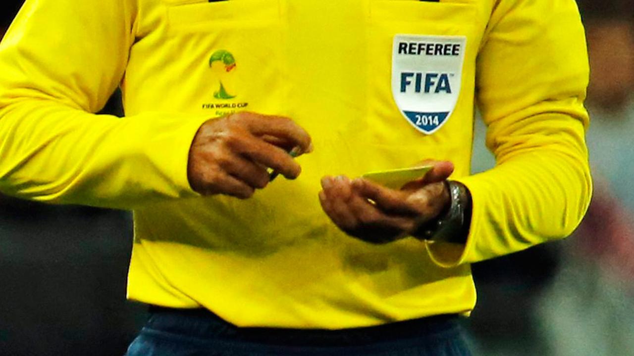 Ein Schiedsrichter zieht gerade eine gelbe Karte.