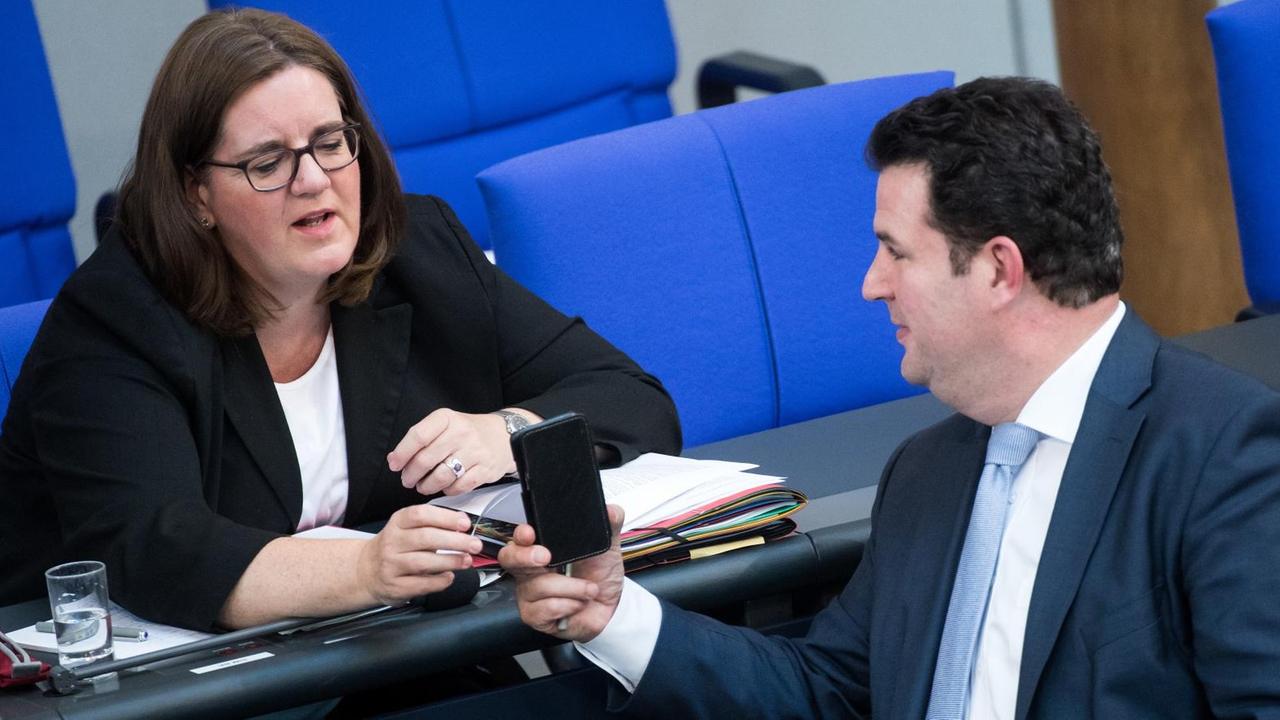 05.07.2018, Berlin: Hubertus Heil (r, SPD), Bundesminister für Arbeit und Soziales, zeigt Kerstin Griese (SPD), Parlamentarische Staatssekretärin beim Bundesminister für Arbeit und Soziales, bei der Plenarsitzung im Deutschen Bundestag etwas auf seinem Smartphone. Höhepunkt der 46. Sitzung der 19. Wahlperiode ist die Verabschiedung des Bundeshaushalts. Zuvor berät das Parlament in seiner letzten Sitzung vor der Sommerpause mehrere Einzeletats. Foto: Bernd von Jutrczenka/dpa | Verwendung weltweit 05.07.2018, Berlin: Hubertus Heil (r, SPD), Bundesminister für Arbeit und Soziales, zeigt Kerstin Griese (SPD), Parlamentarische Staatssekretärin beim Bundesminister für Arbeit und Soziales, bei der Plenarsitzung im Deutschen Bundestag etwas auf seinem Smartphone. Höhepunkt der 46. Sitzung der 19. Wahlperiode ist die Verabschiedung des Bundeshaushalts. Zuvor berät das Parlament in seiner letzten Sitzung vor der Sommerpause mehrere Einzeletats. Foto: Bernd von Jutrczenka/dpa | Verwendung weltweit