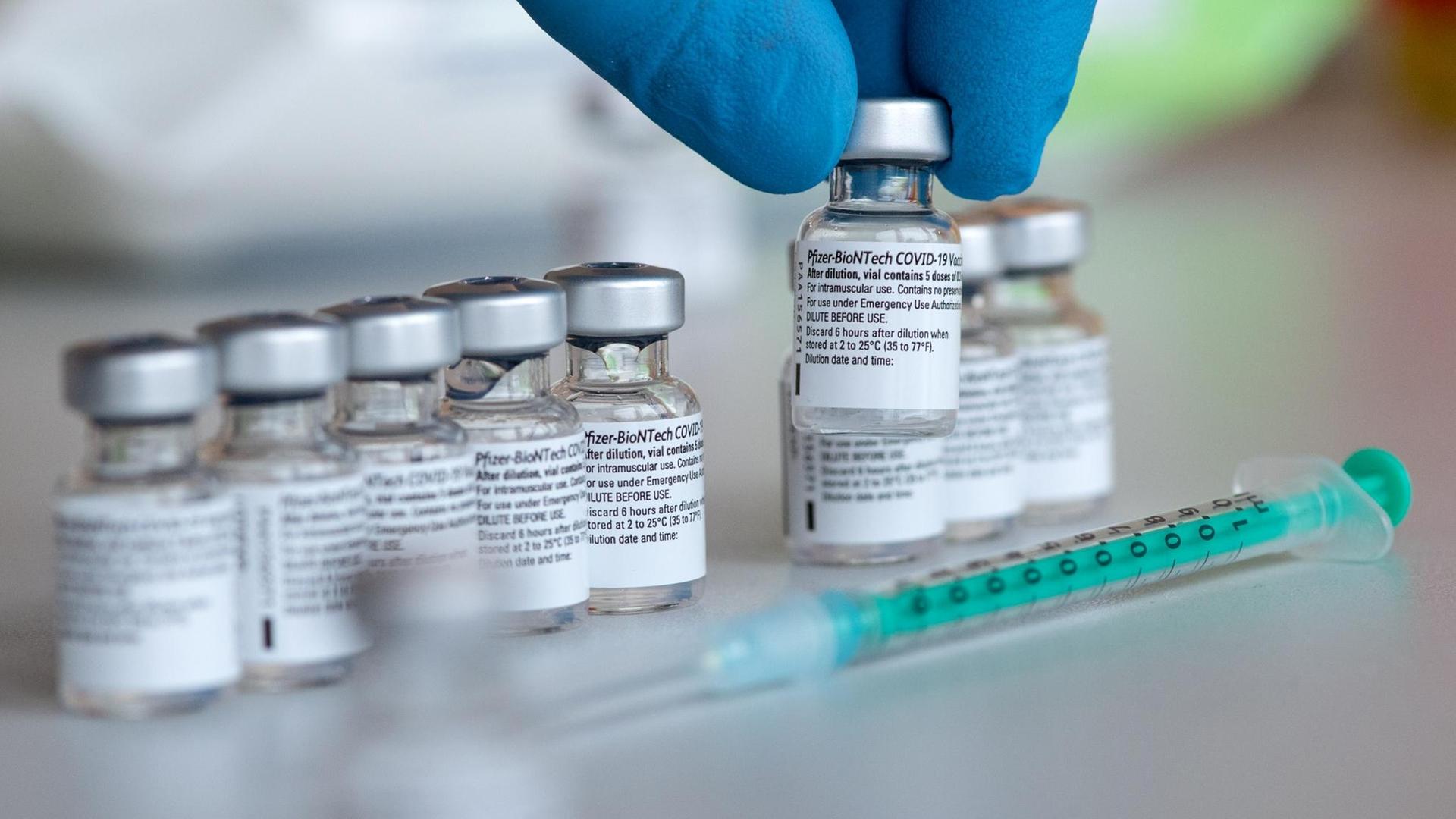 Leere Ampullen des Impfstoffs von Biontech/Pfizer gegen das Corona-Virus SARS-CoV-2 stehen in einem Impfzentrum nach der Vorberietung der Spritzen auf einem Tisch.