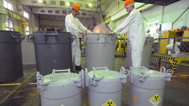Mitarbeiter in der russischen kerntechnischen Anlage Majak neben Behältnissen, die laut Kennzeichnung radioaktives Material enthalten