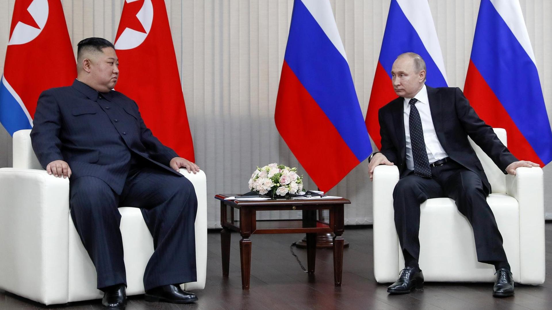 Nordkoreas Machhthaber Kim trifft Russlands Präsidenten Putin. Die beiden sitzen in Ledersesseln vor den Flaggen ihrer Länder und sehen sich an. Nordkoreas Machhthaber Kim trifft Russlands Präsidenten Putin. Die beiden sitzen in Ledersesseln vor den Flaggen ihrer Länder und sehen sich an.
