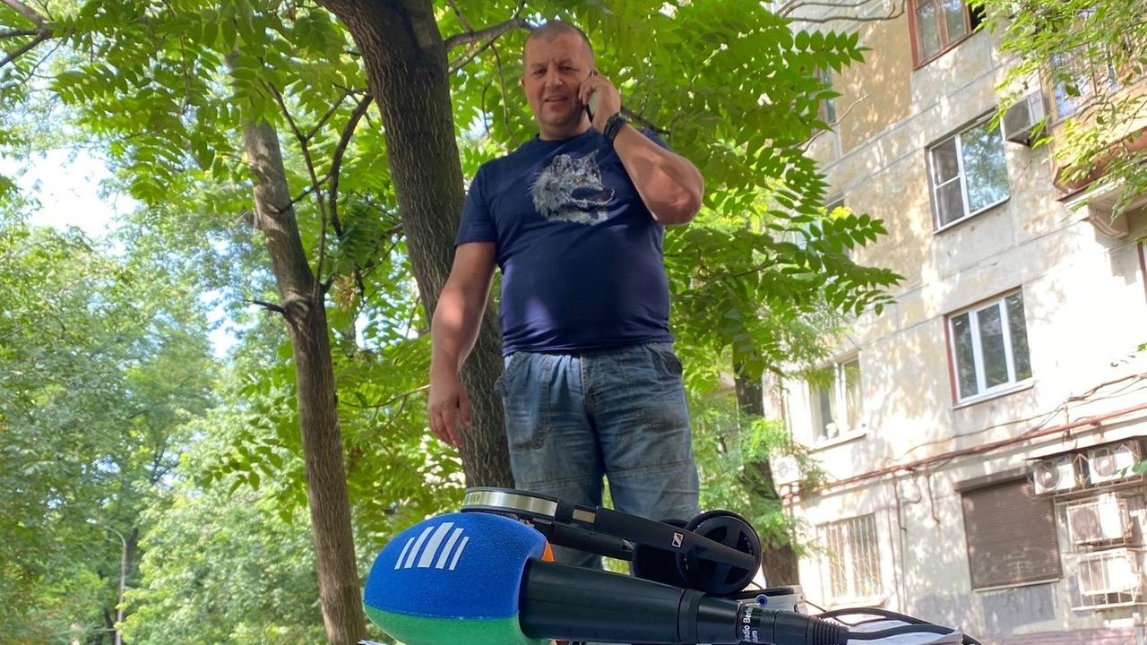 Uni-Dozent und Kampfsportler Olexander Pritúla aus Saporischschja: kahlrasierter Kopf, enges blaues T-Shirt, Bauansatz, Handy in der Hand. Uni-Dozent und Kampfsportler Olexander Pritúla aus Saporischschja: kahlrasierter Kopf, enges blaues T-Shirt, Bauansatz, Handy in der Hand.